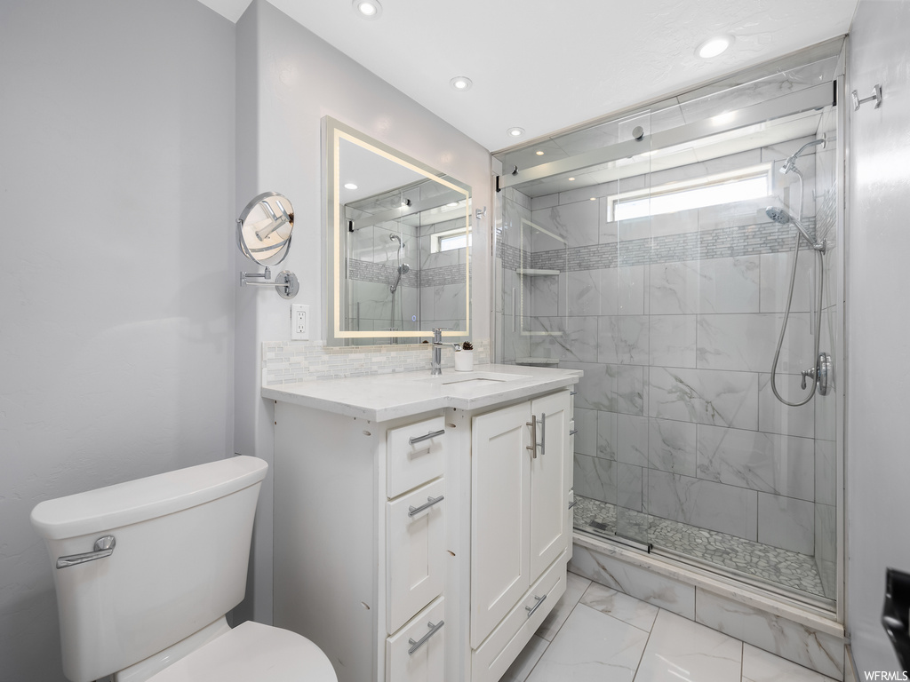Bathroom featuring a shower with shower door, large vanity, toilet, and tile floors