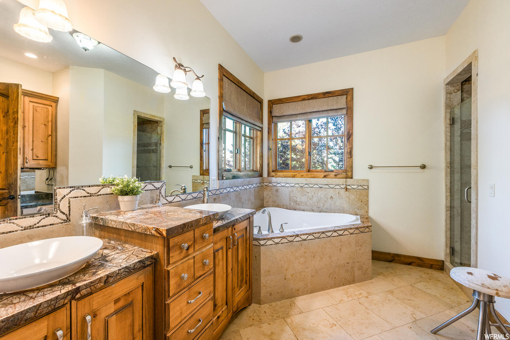 Bathroom with tile floors, dual sinks, independent shower and bath, and vanity with extensive cabinet space