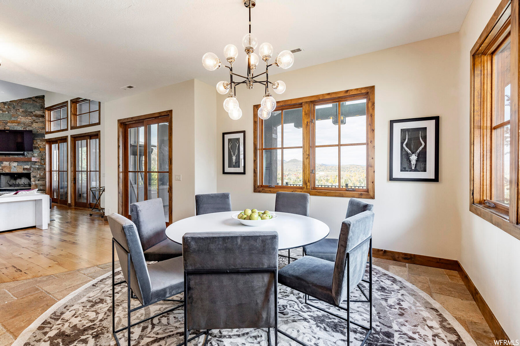 Dining area featuring light hardwood / wood-style floors, a fireplace, and a notable chandelier