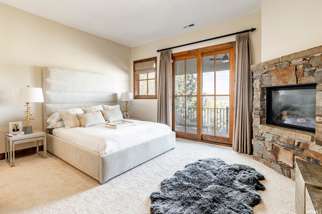 Bedroom with access to outside, a fireplace, and light colored carpet