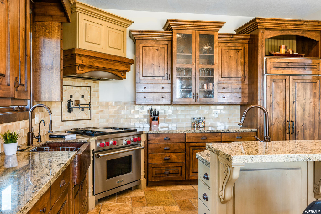Kitchen featuring light tile flooring, tasteful backsplash, premium range hood, and high quality appliances
