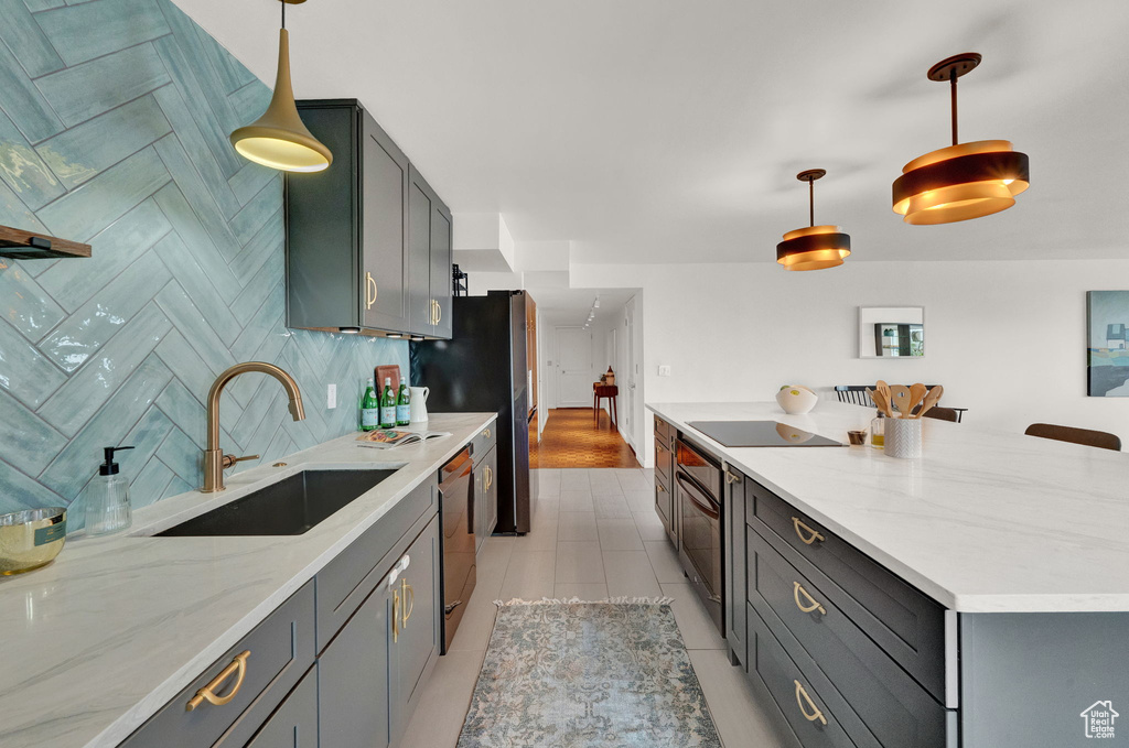 Kitchen with sink, light tile floors, hanging light fixtures, light stone countertops, and tasteful backsplash