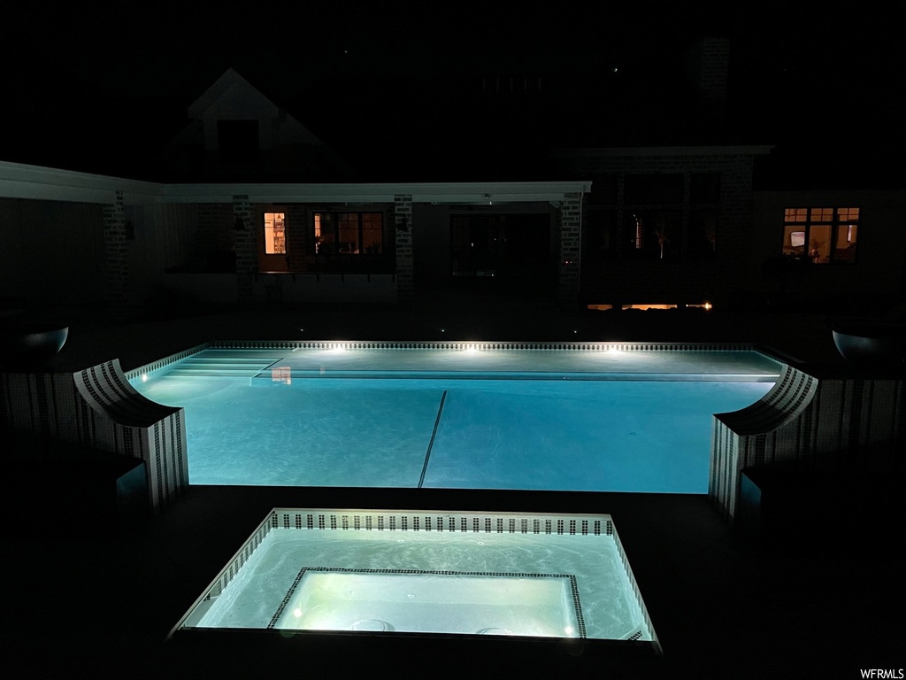 Pool at twilight featuring an in ground hot tub and a patio