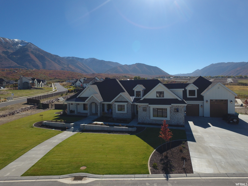 View of front of property with a front lawn, a mountain view, and a garage