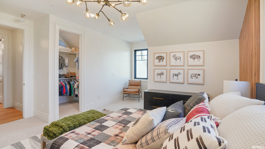 Carpeted bedroom with vaulted ceiling, a spacious closet, a closet, and a notable chandelier