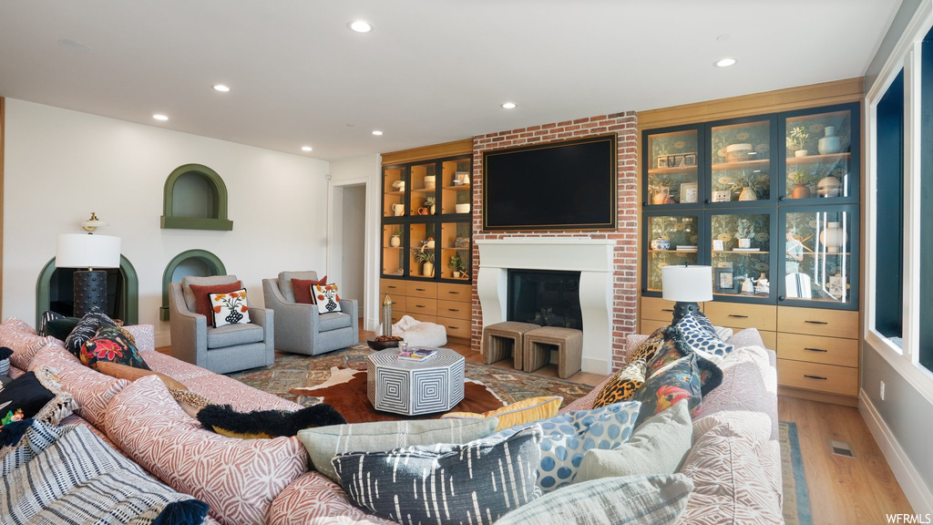 Living room featuring light hardwood / wood-style floors, a fireplace, and brick wall