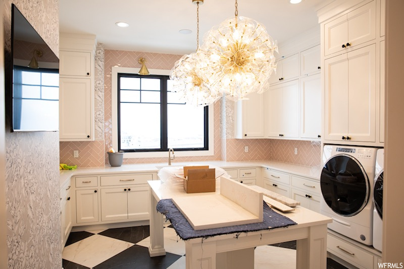 Washroom with plenty of natural light, cabinets, a notable chandelier, and independent washer and dryer