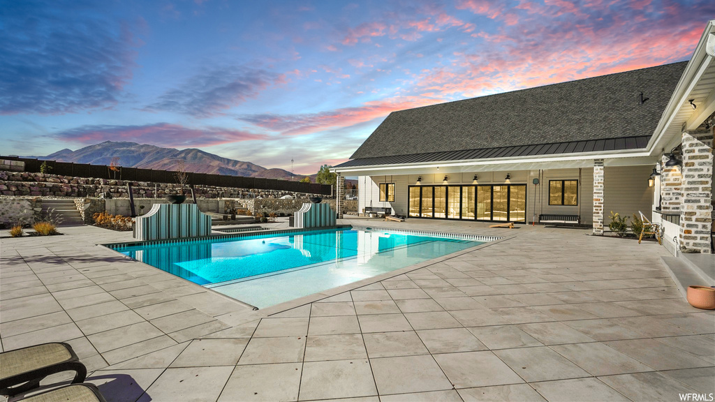 Pool at dusk featuring a patio area and a mountain view