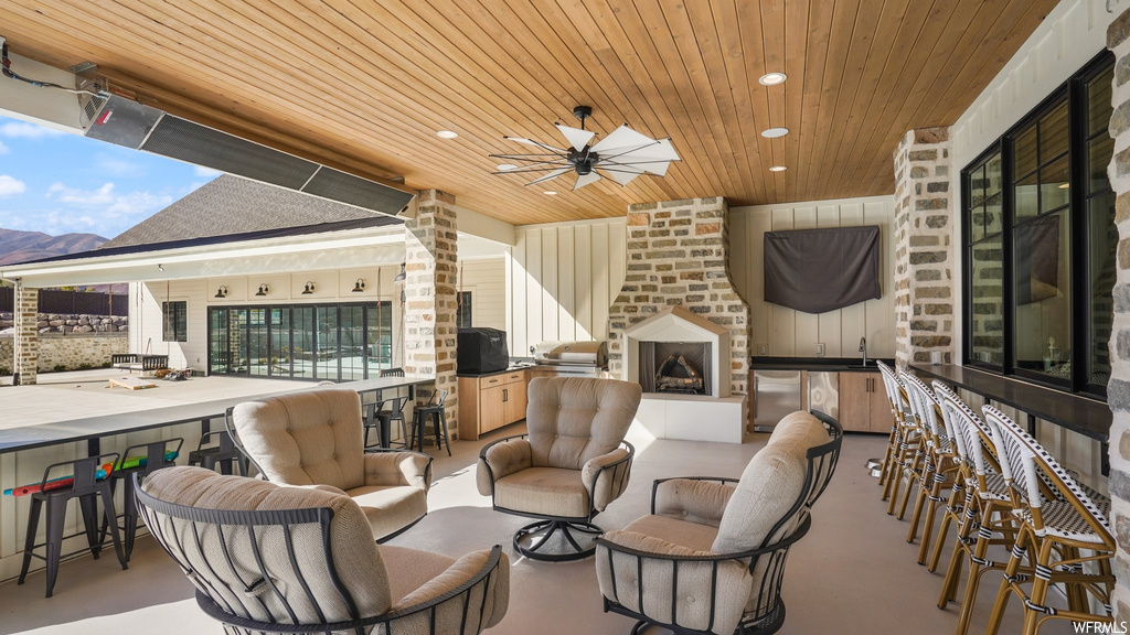 View of patio / terrace featuring ceiling fan, area for grilling, a bar, and a fireplace