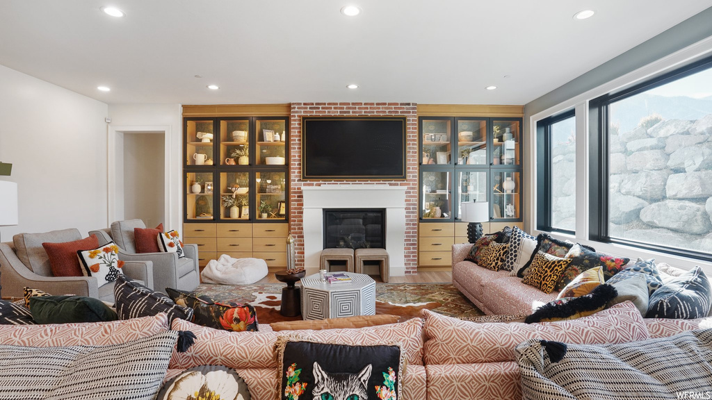 Living room with a fireplace, brick wall, and hardwood / wood-style flooring