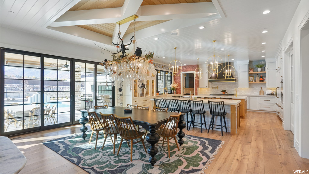 Dining space featuring a chandelier, light hardwood / wood-style floors, and beamed ceiling