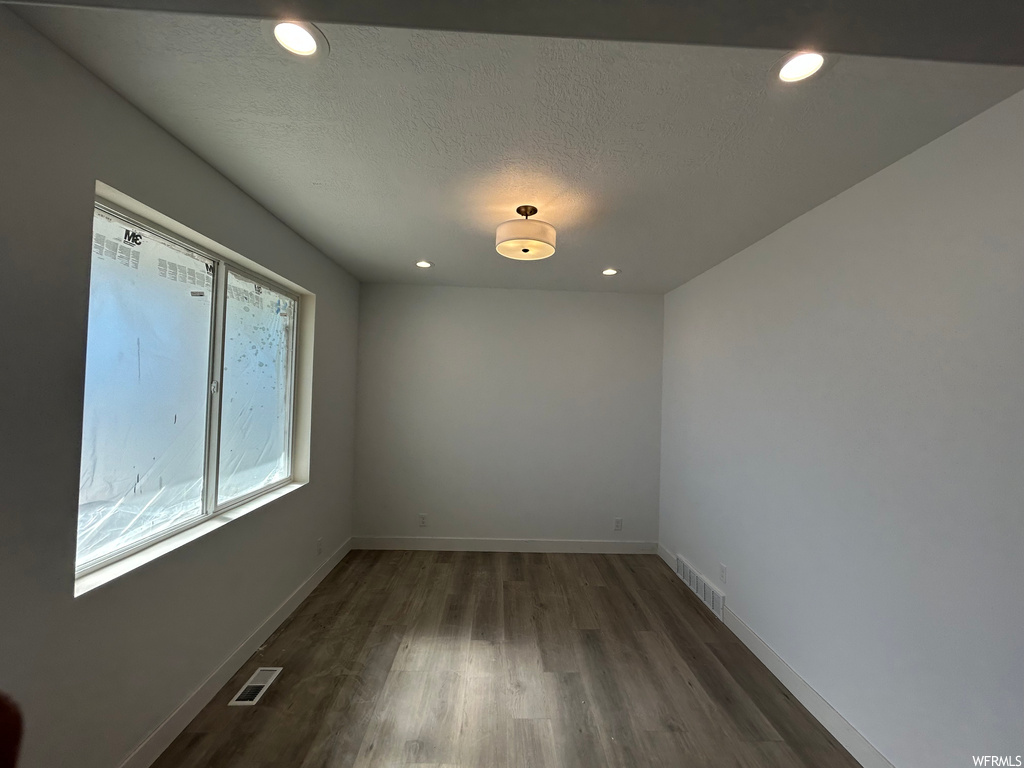 Empty room featuring plenty of natural light, dark hardwood / wood-style flooring, and a textured ceiling