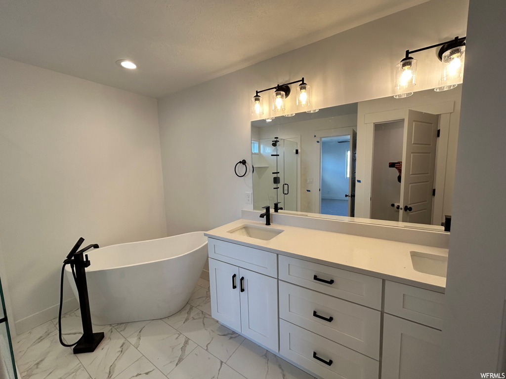 Bathroom with double vanity, a bath, and tile floors