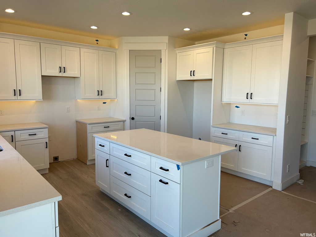 Kitchen featuring light wood-type flooring, a center island, and white cabinets