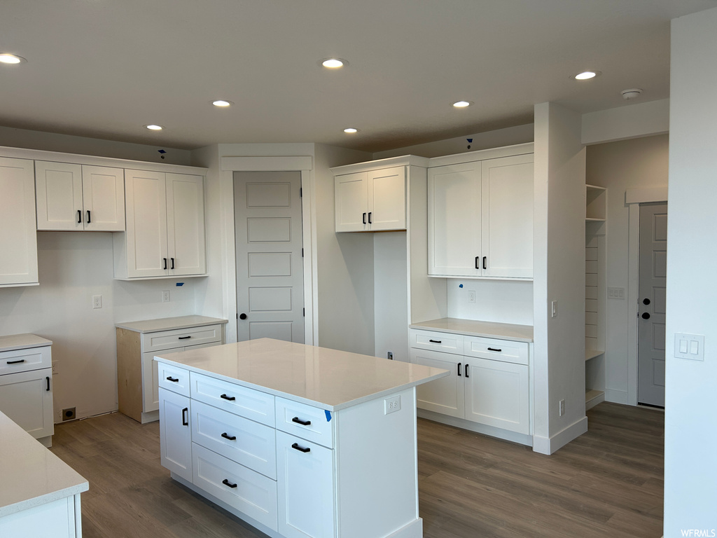 Kitchen featuring hardwood / wood-style flooring, a center island, and white cabinetry