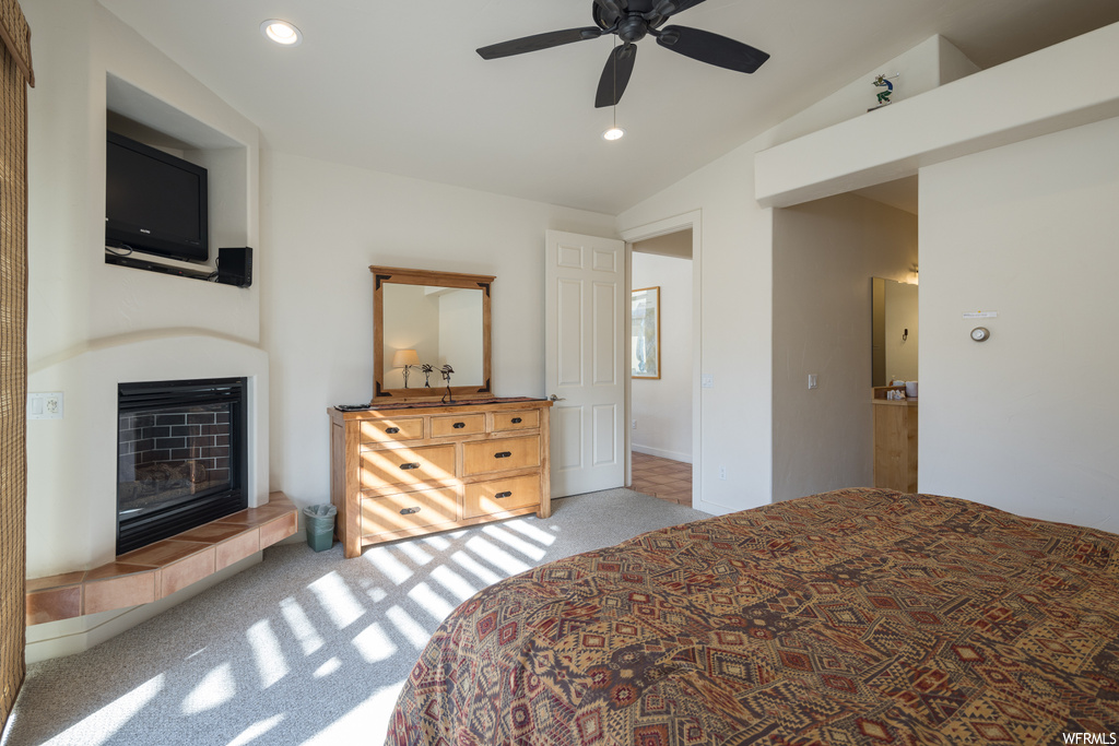 Bedroom with light carpet, a fireplace, ceiling fan, and vaulted ceiling