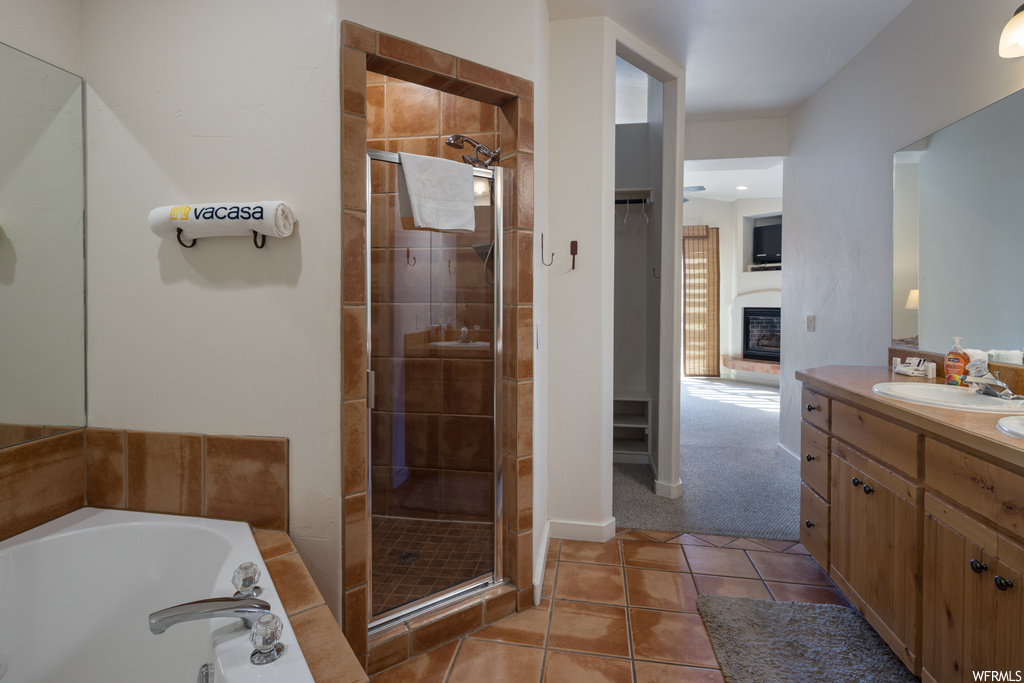 Bathroom featuring vanity, tile flooring, a fireplace, and separate shower and tub