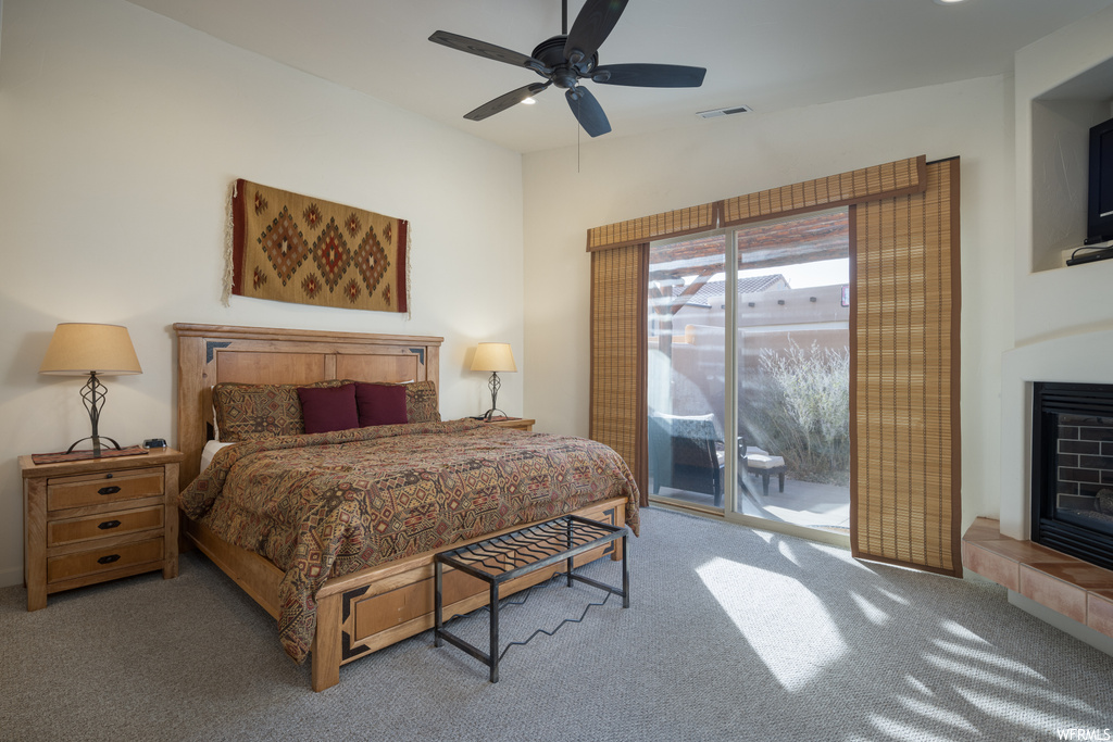 Carpeted bedroom featuring access to exterior, ceiling fan, lofted ceiling, and a fireplace