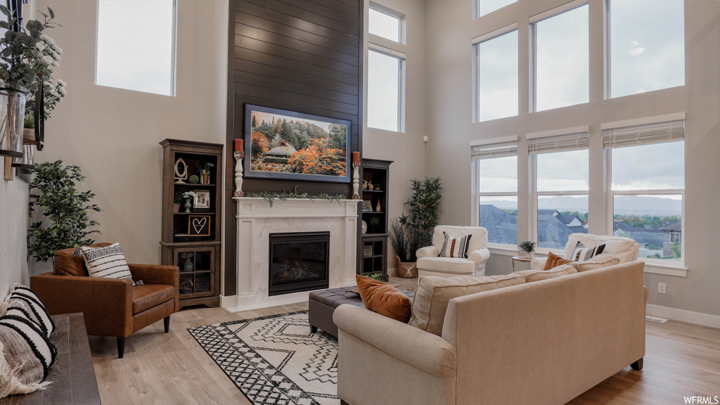 Living room featuring a towering ceiling, a fireplace, and light hardwood / wood-style flooring