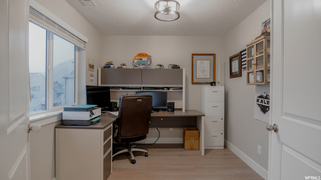 Office area with a wealth of natural light, a textured ceiling, and light hardwood / wood-style flooring