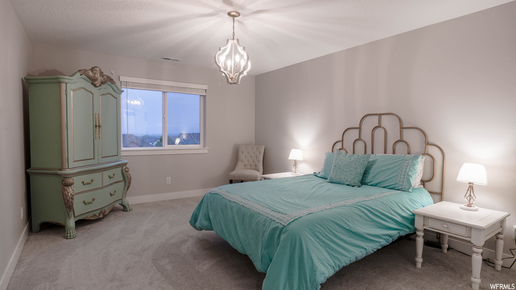 Bedroom with an inviting chandelier and light colored carpet