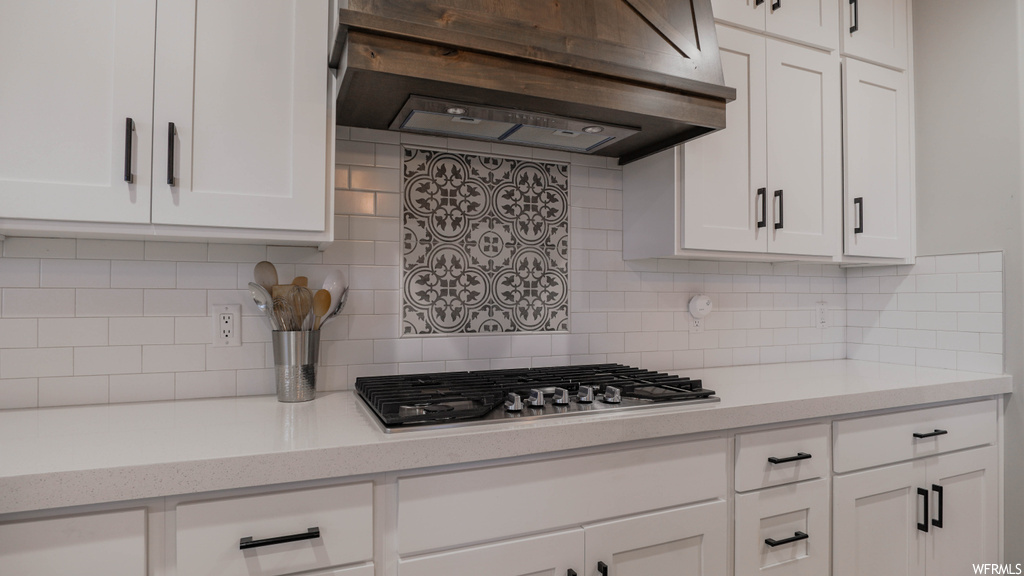 Kitchen featuring backsplash and white cabinets
