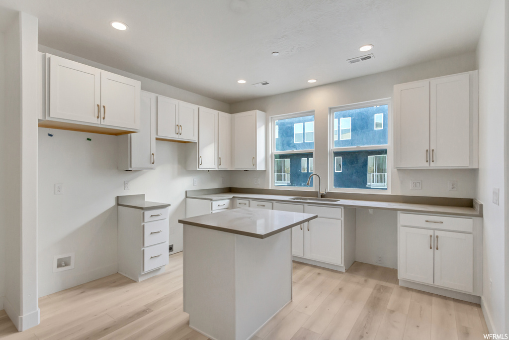 Kitchen featuring a center island, white cabinets, sink, and light hardwood / wood-style floors