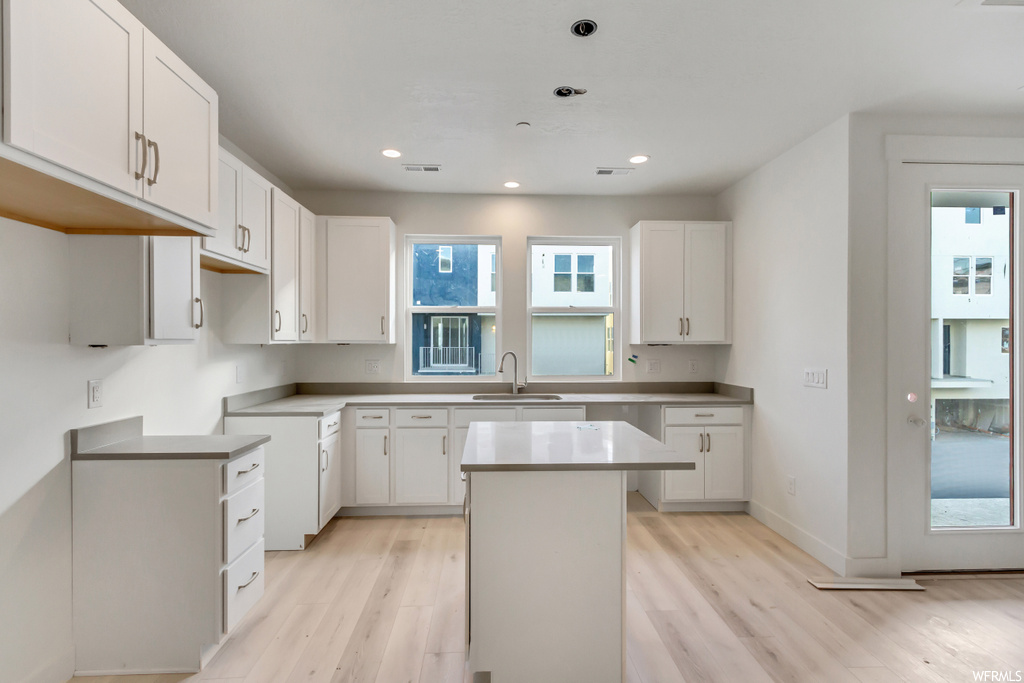 Kitchen with a center island, white cabinets, and light hardwood / wood-style floors