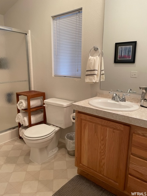 Bathroom with tile flooring, an enclosed shower, large vanity, and toilet