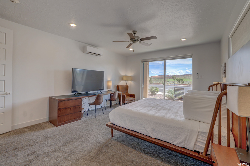 Bedroom with light colored carpet, a wall mounted AC, ceiling fan, and access to outside