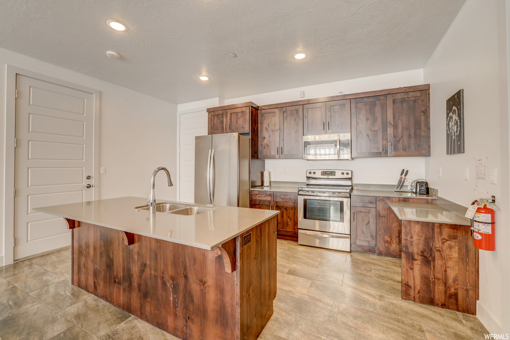 Kitchen featuring sink, appliances with stainless steel finishes, and an island with sink