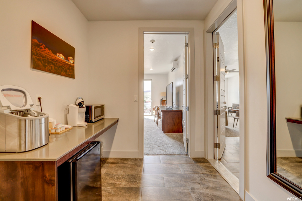 Corridor featuring beverage cooler, light tile floors, and an AC wall unit