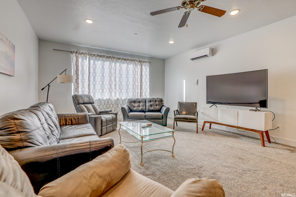 Carpeted living room featuring a wall mounted AC and ceiling fan