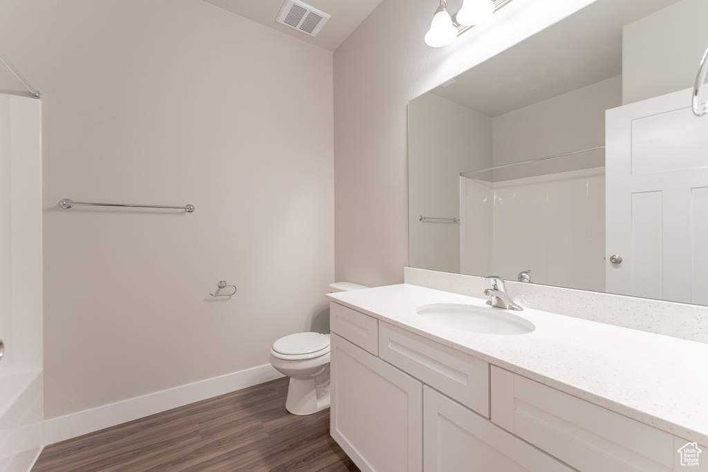 Full bathroom with toilet, vanity, hardwood / wood-style floors, and shower / bathtub combination