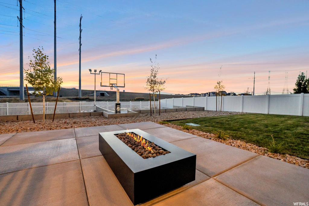 Patio terrace at dusk with a lawn and a fire pit