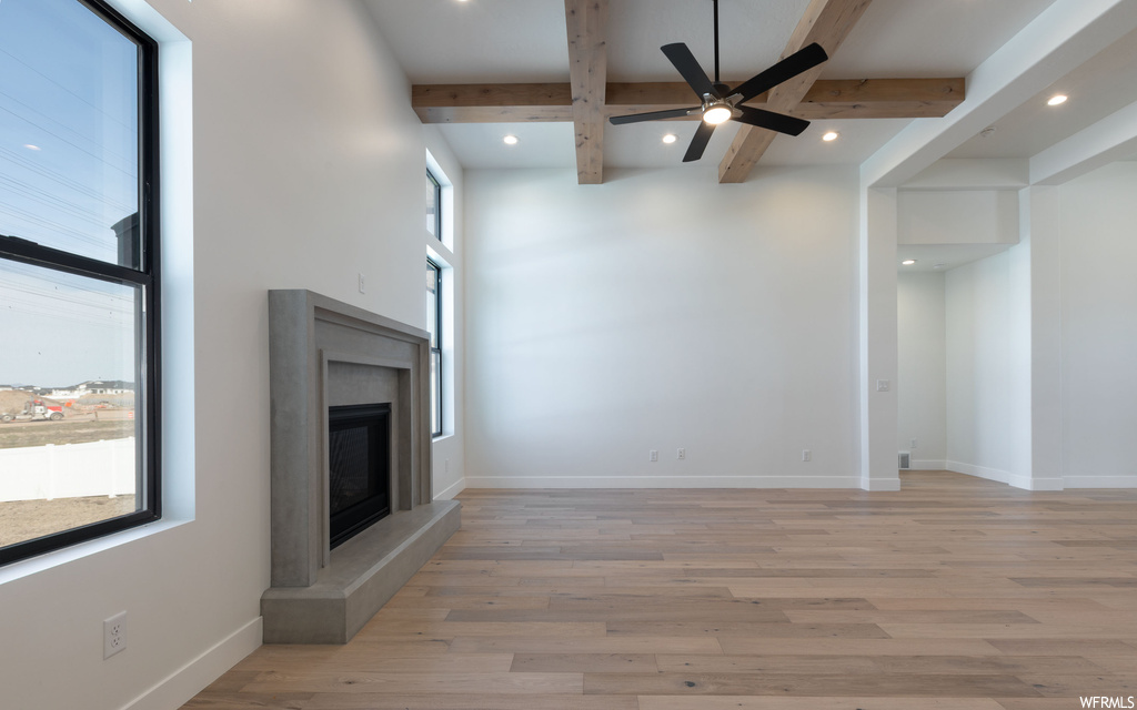 Unfurnished living room with plenty of natural light, ceiling fan, a fireplace, and light hardwood / wood-style flooring