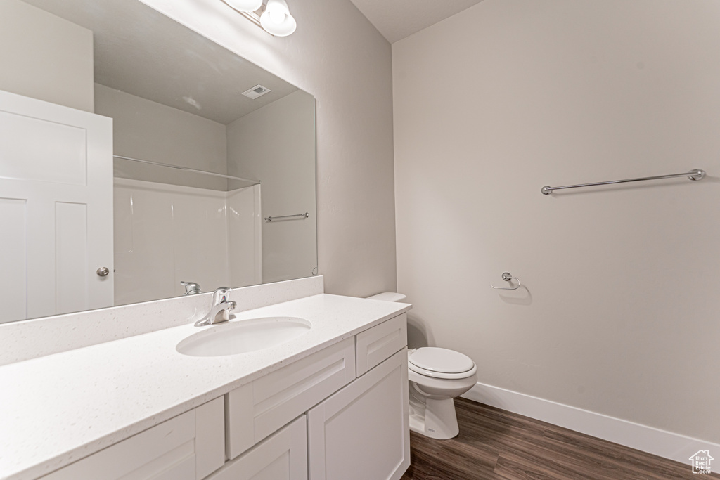 Bathroom featuring large vanity, toilet, and hardwood / wood-style flooring