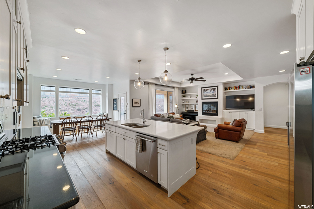 Kitchen with sink, light hardwood / wood-style floors, appliances with stainless steel finishes, and white cabinets