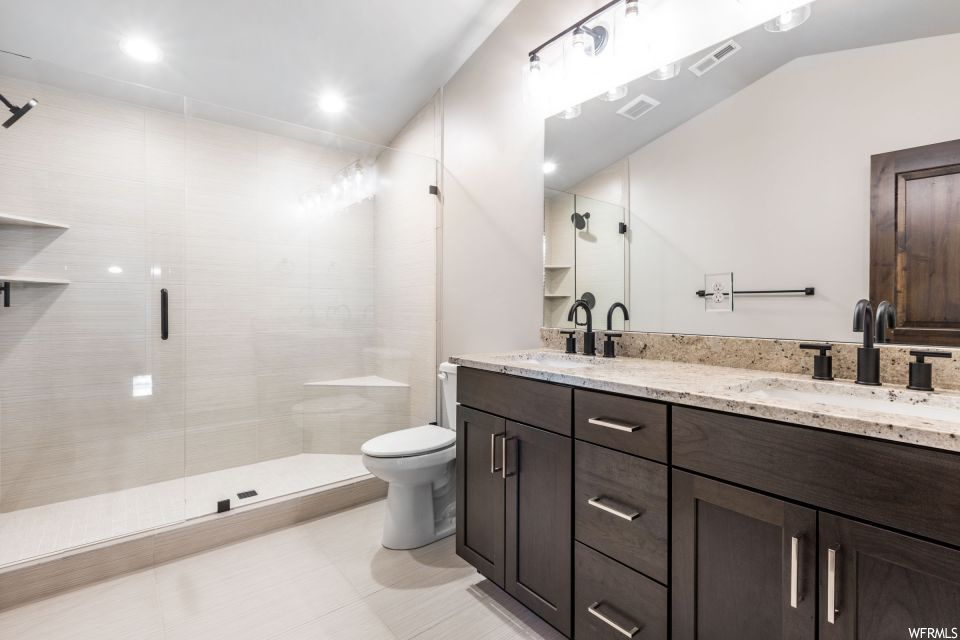 Bathroom featuring an enclosed shower, tile flooring, and dual vanity