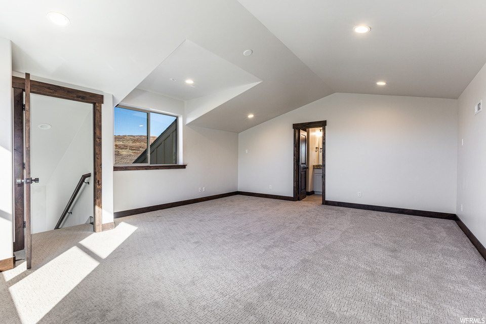 Bonus room with light colored carpet and lofted ceiling