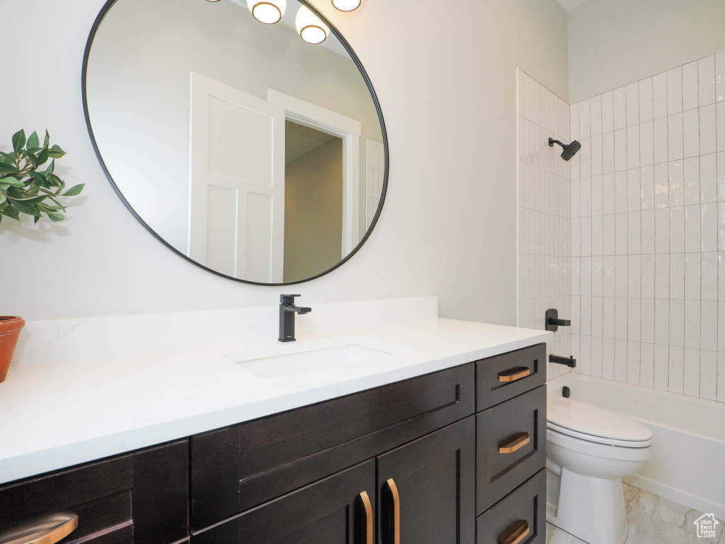 Full bathroom featuring large vanity, tiled shower / bath, tile floors, and toilet