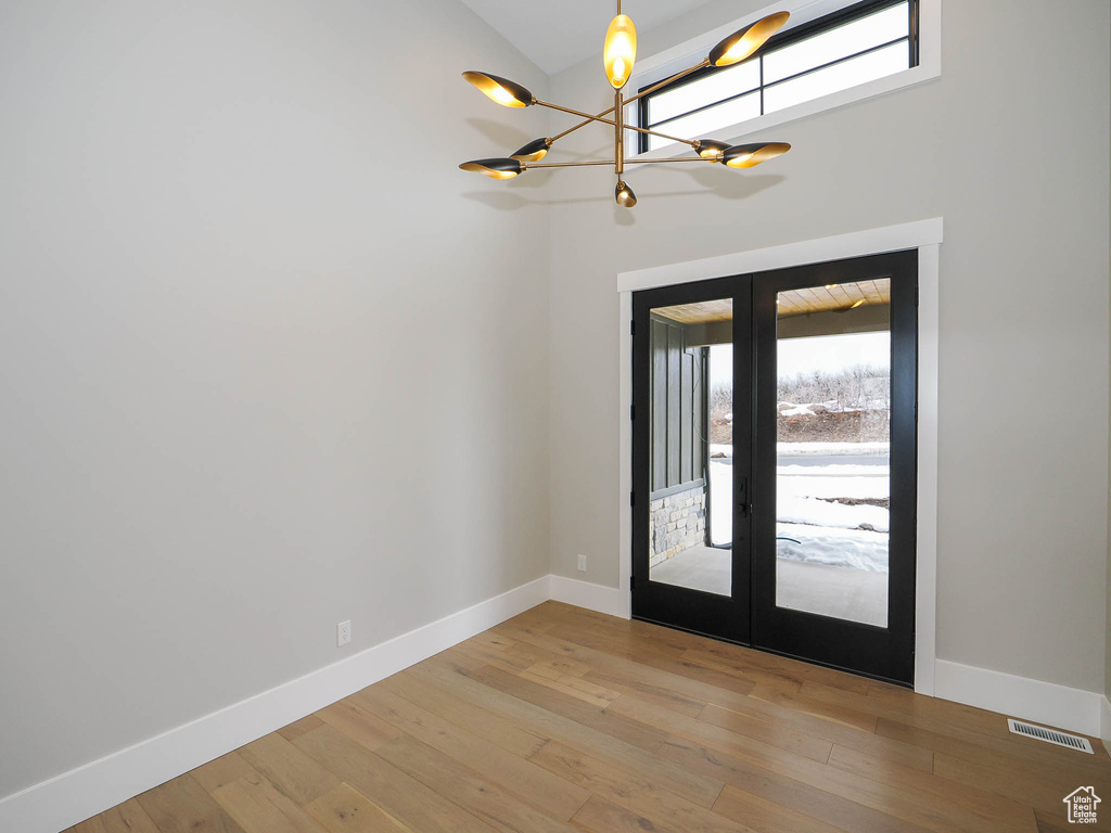 Entrance foyer featuring light wood-type flooring, a notable chandelier, and french doors
