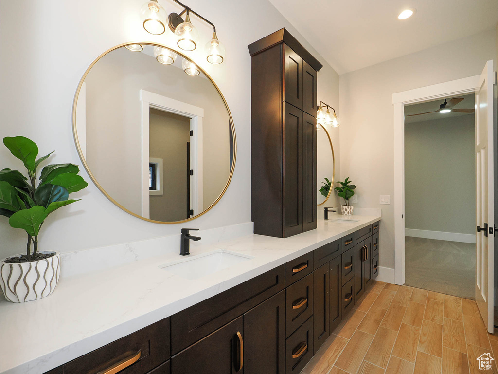 Bathroom with hardwood / wood-style flooring, ceiling fan, double sink, and vanity with extensive cabinet space