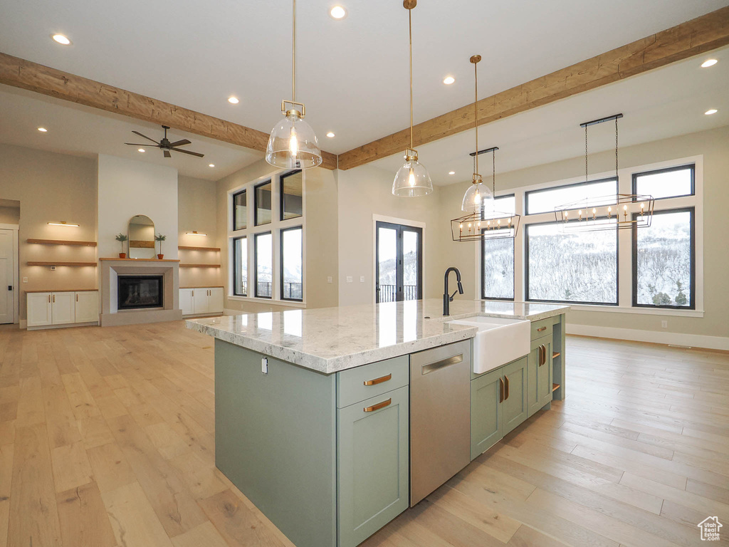Kitchen featuring light hardwood / wood-style floors, a center island with sink, hanging light fixtures, sink, and stainless steel dishwasher
