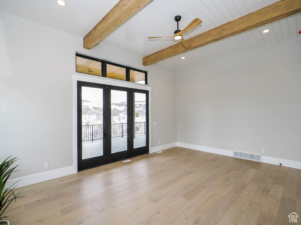 Unfurnished room featuring light wood-type flooring, beam ceiling, ceiling fan, and french doors