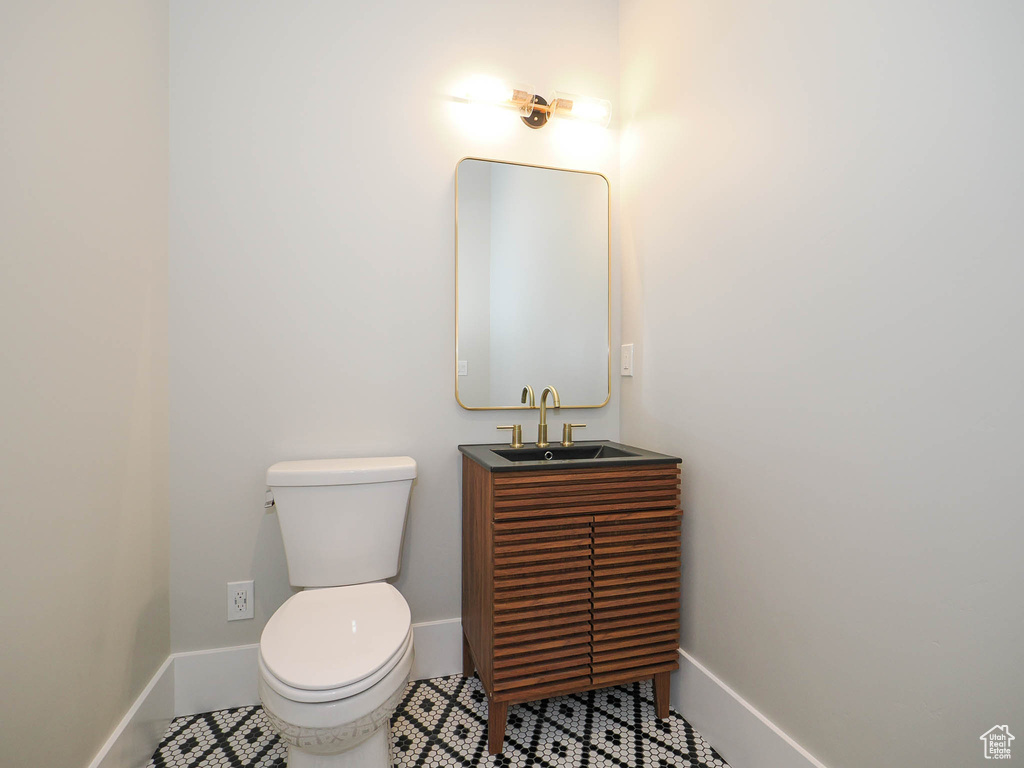 Bathroom with toilet, tile floors, and vanity with extensive cabinet space
