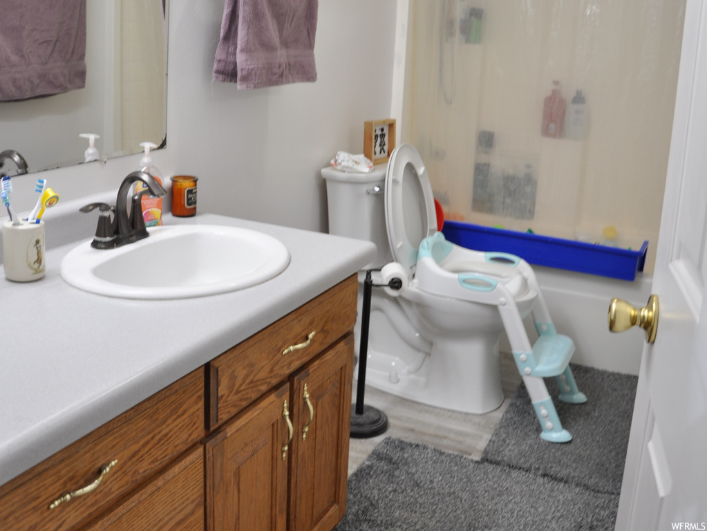 Full bathroom featuring vanity, shower / bath combination with curtain, toilet, and hardwood / wood-style flooring