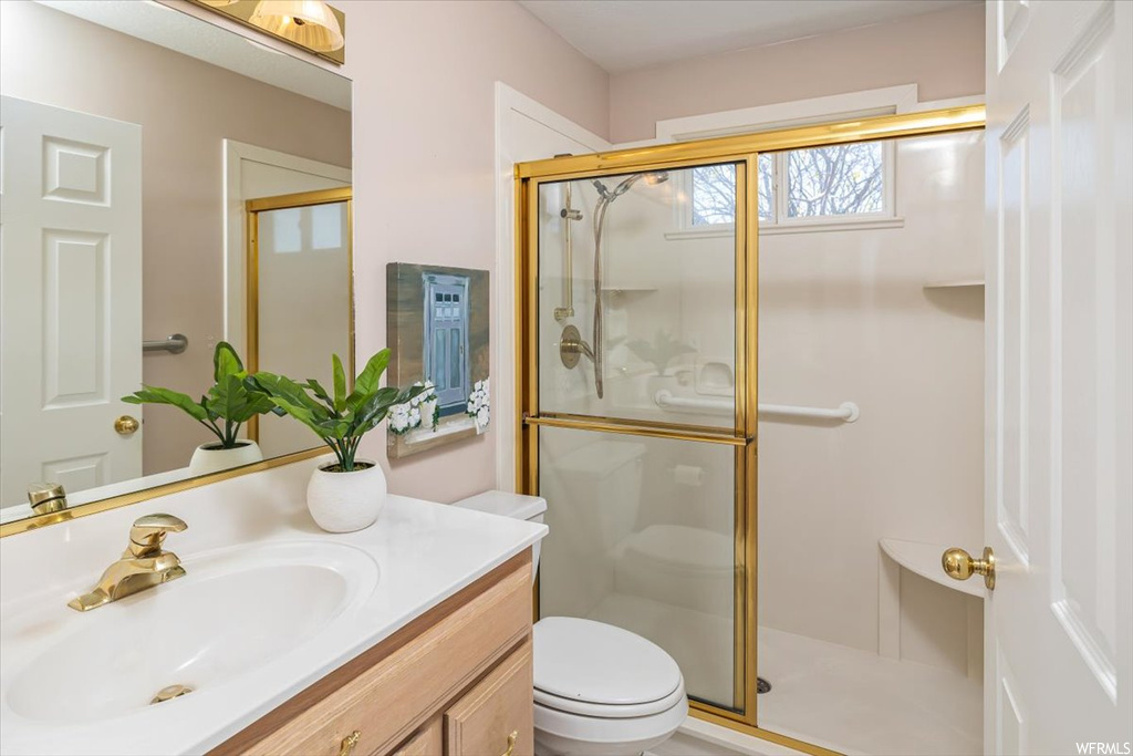 Bathroom with an enclosed shower, vanity with extensive cabinet space, and toilet