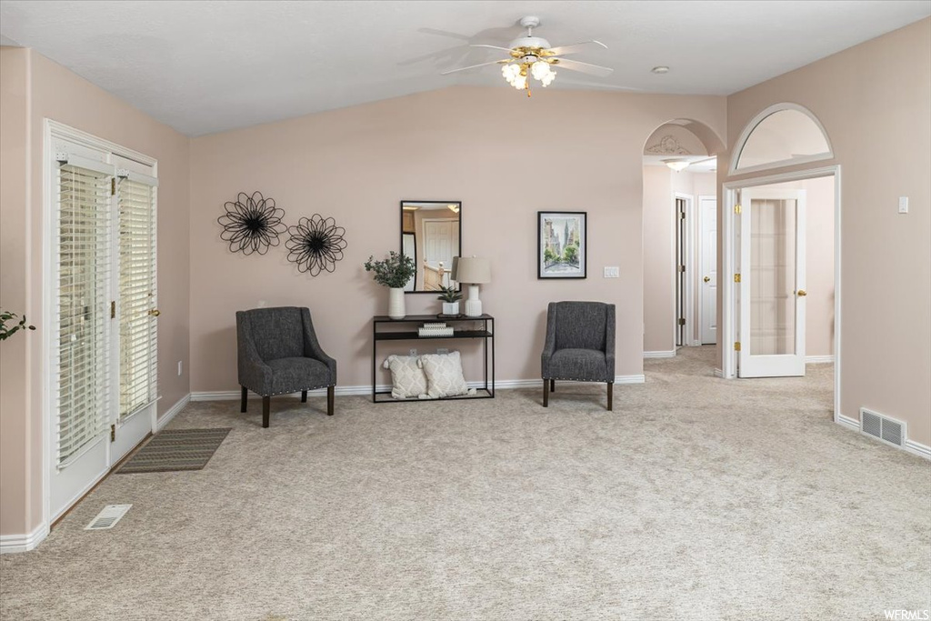 Sitting room featuring light carpet, ceiling fan, and vaulted ceiling