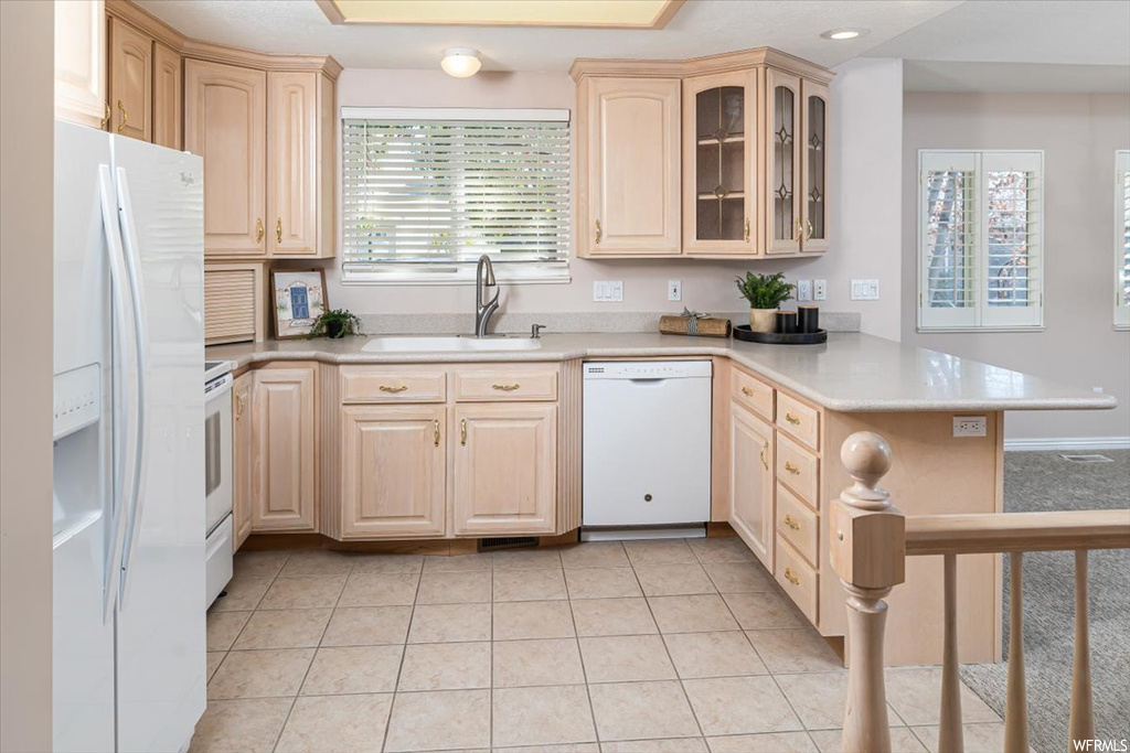 Kitchen featuring light brown cabinets, sink, kitchen peninsula, light tile floors, and white appliances
